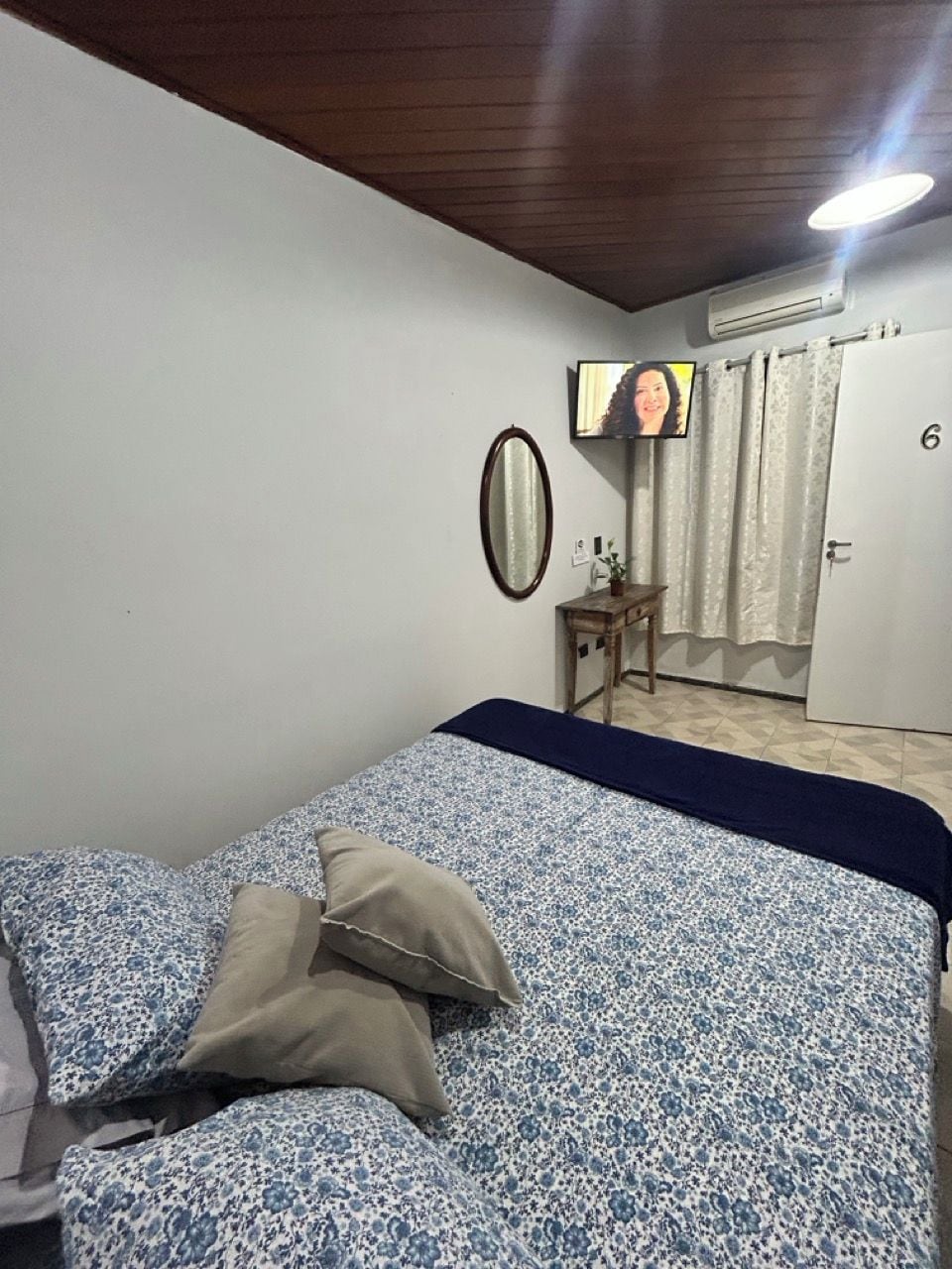A bedroom with a bed, a television, a small table, and a door.