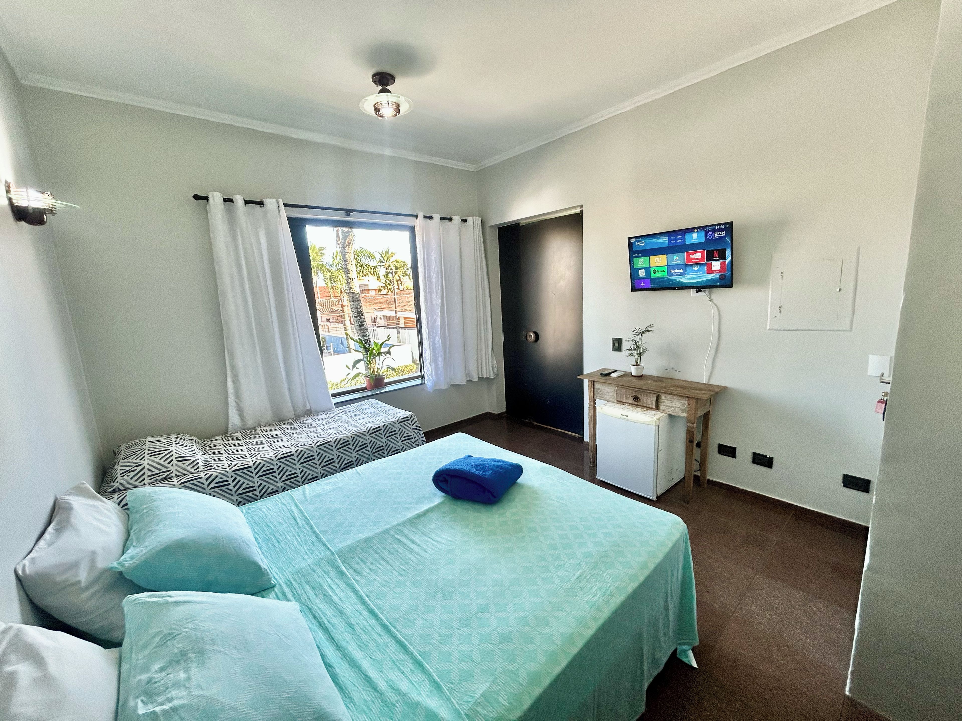 Ein Hotelzimmer mit Bett, Schreibtisch, Fernseher und einem Fenster mit Vorhängen.