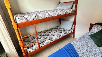 Uma cama beliche com roupa de cama estampada, um cobertor azul, um quadro na parede e um aparelho de ar condicionado.