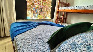 Een kamer met een bed, een raam en een stapelbed.