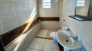 Een badkamer met toilet, wastafel en spiegel.