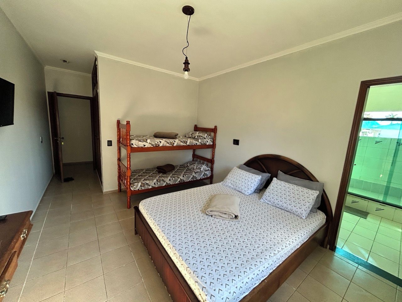 A bedroom with a single bed, a wooden bunk bed, and a small desk.