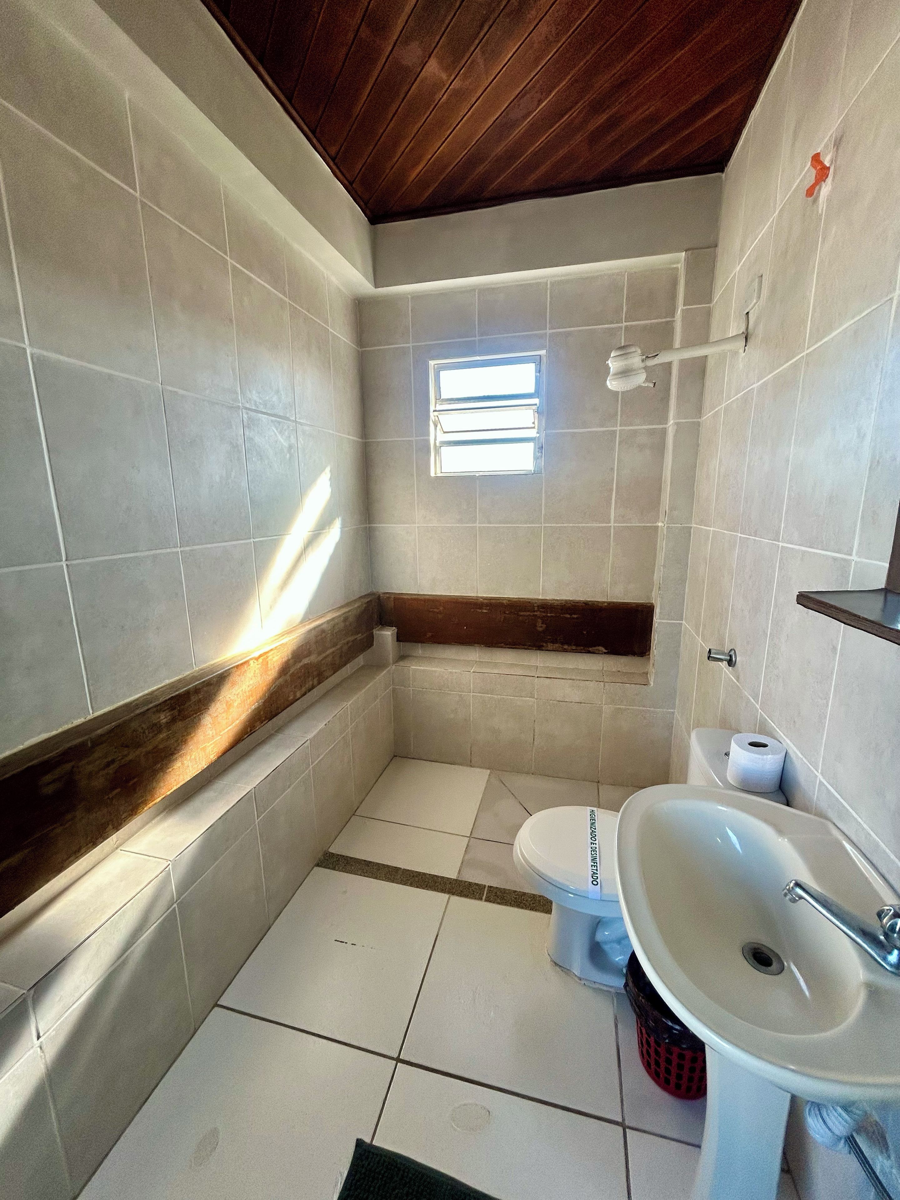 A small bathroom with a toilet, sink, and a window.