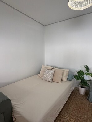 A single bed with a beige bedspread, two pillows, a potted plant, and a woven light fixture. - Benalbali Beach House, Benalmádena Costa, 200 m from the beach (Benalmádena)