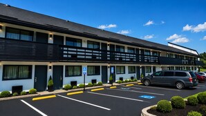 Een meerlaags hotel met een parkeerplaats, parkeerplaatsen voor gehandicapten, en een geparkeerde auto op de plaats.
