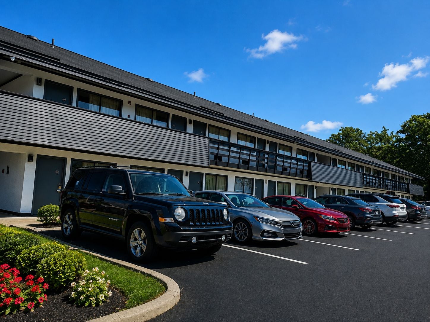 A parking lot with multiple cars, a building with a flat roof, and a clear sky.