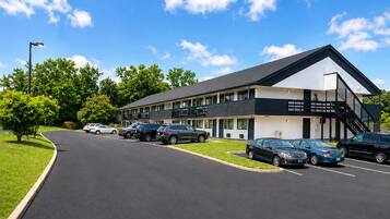 A two-story motel with a parking lot, a covered walkway, and a clear sky.