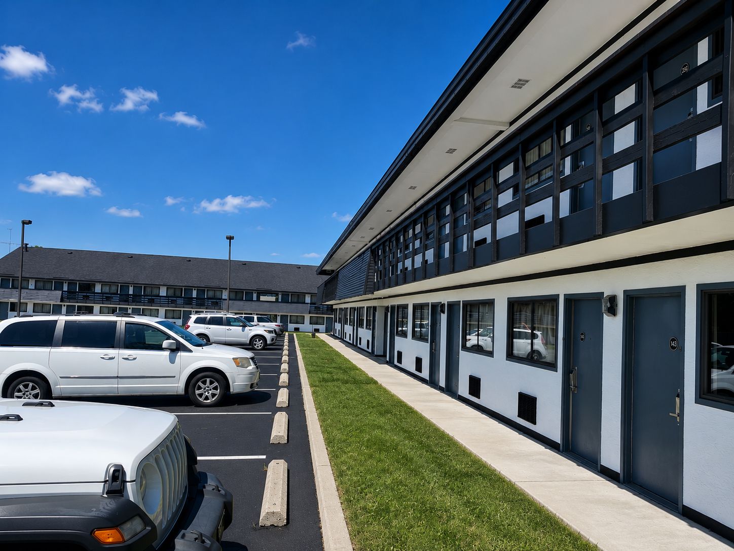 Un bâtiment moderne doté d’un parking et d’une rangée de voitures garées.
