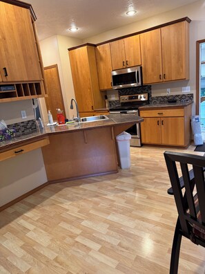 A kitchen with wooden cabinets, a stainless steel sink, and a microwave.