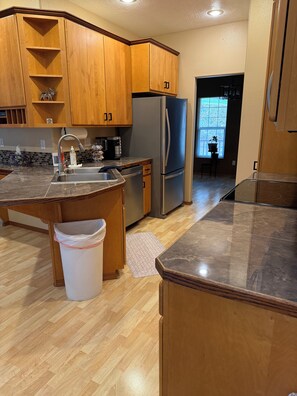 Una cocina con armarios de madera, un refrigerador de acero inoxidable, un lavamanos y una encimera.