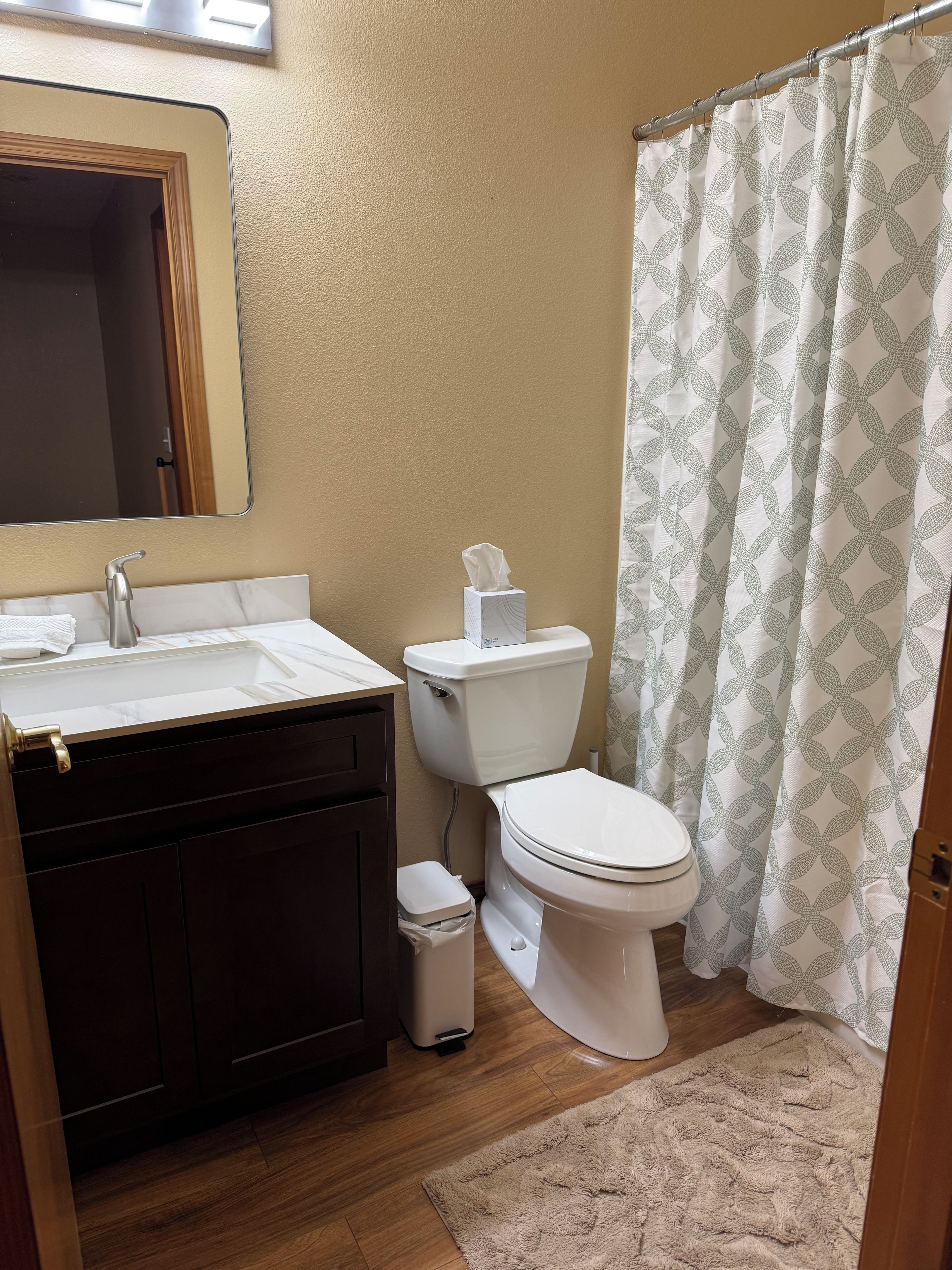 A bathroom with a toilet, sink, and mirror.