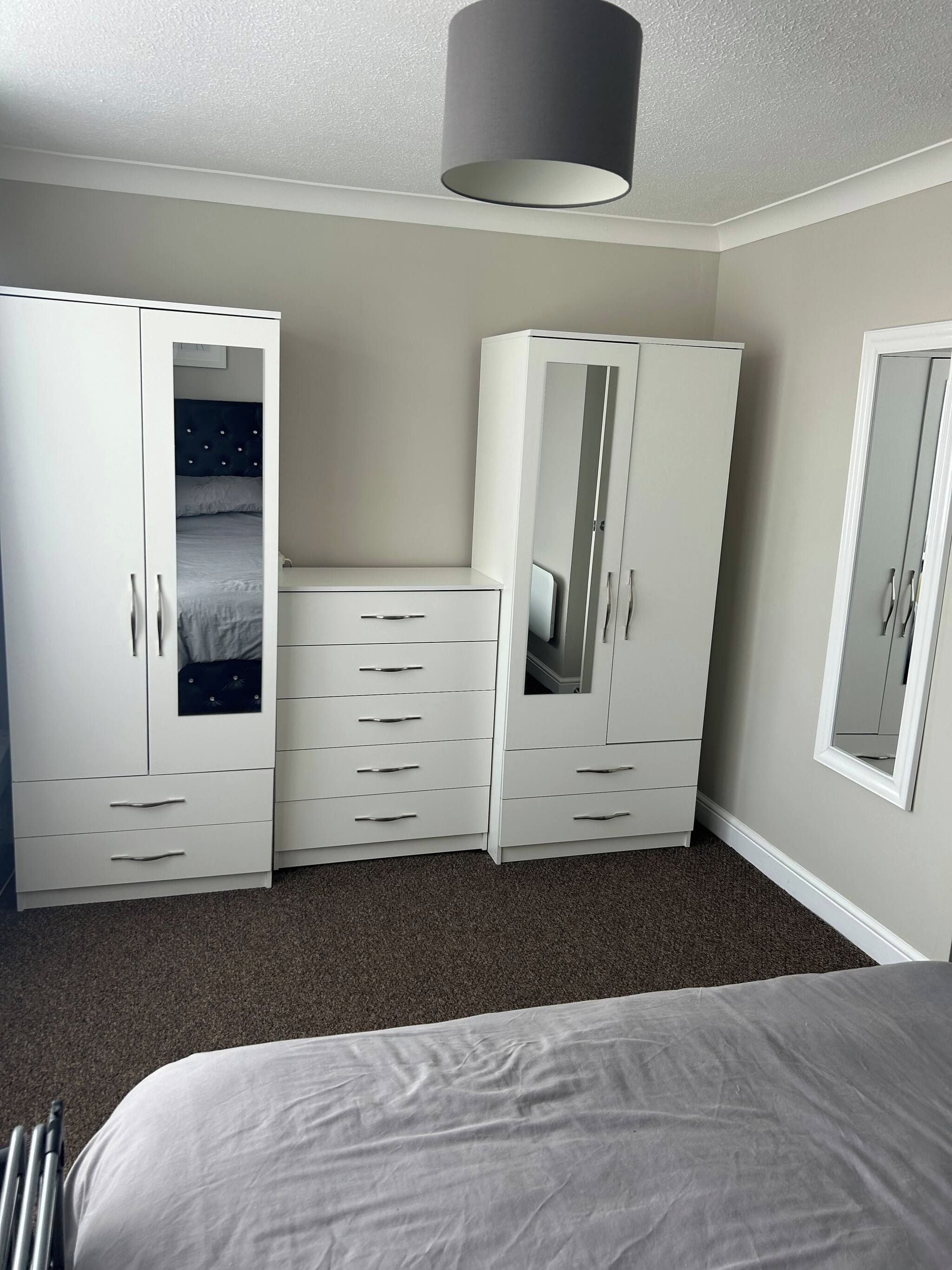 A bedroom with a bed, two wardrobes, and a mirror.