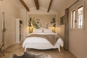 A bedroom with a large bed, wooden beams on the ceiling, a wall-mounted plant, and a window with curtains. - L'Olivette de Callian - Provence Home with Panoramic View (Callian)
