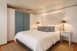A bedroom with a bed, two bedside tables, a decorative wall panel, and a blue wardrobe.