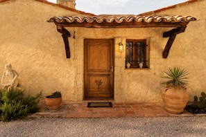 A rustic building with a wooden door, a stone statue, and potted plants. - L'Olivette de Callian - Provence Home with Panoramic View (Callian)