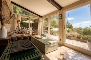A spacious living area with a large window, a green piano, and a comfortable seating arrangement. - L'Olivette de Callian - Provence Home with Panoramic View (Callian)