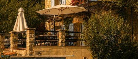 A stone building with a pool, outdoor seating, and a covered patio area.
