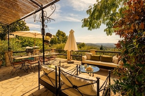Une terrasse extérieure avec une piscine, un espace salon et une vue sur la campagne.