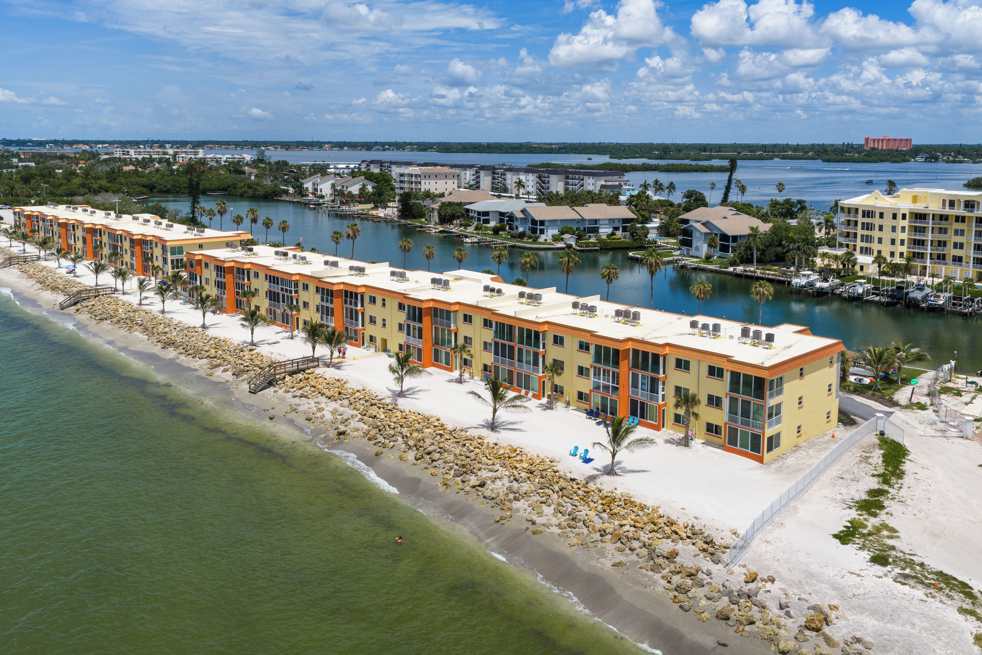 A beachfront hotel with multiple-story buildings, a sandy beach, and a marina.