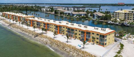 Un hotel frente a la playa con edificios de varios pisos, una playa de arena y un puerto deportivo.