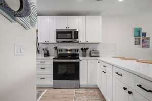 A modern kitchen with white cabinets, a stainless steel oven, a microwave, and a toaster. - Siesta Key - Ground Floor Gulf-Front Retreat - 2 BR – Free Boat Docks (Siesta Key)