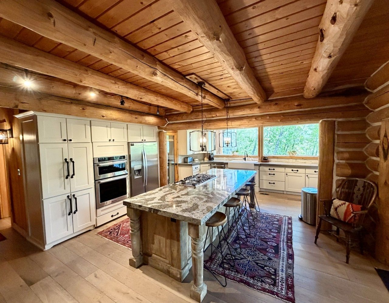A spacious kitchen with a large island, white cabinetry, and a stone countertop.