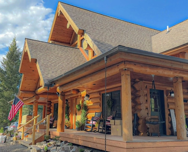 A log cabin with a porch, a flag, and a ladder.