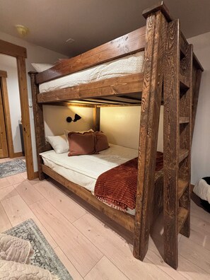 A bunk bed with a wooden frame, a white mattress, and a brown blanket.
