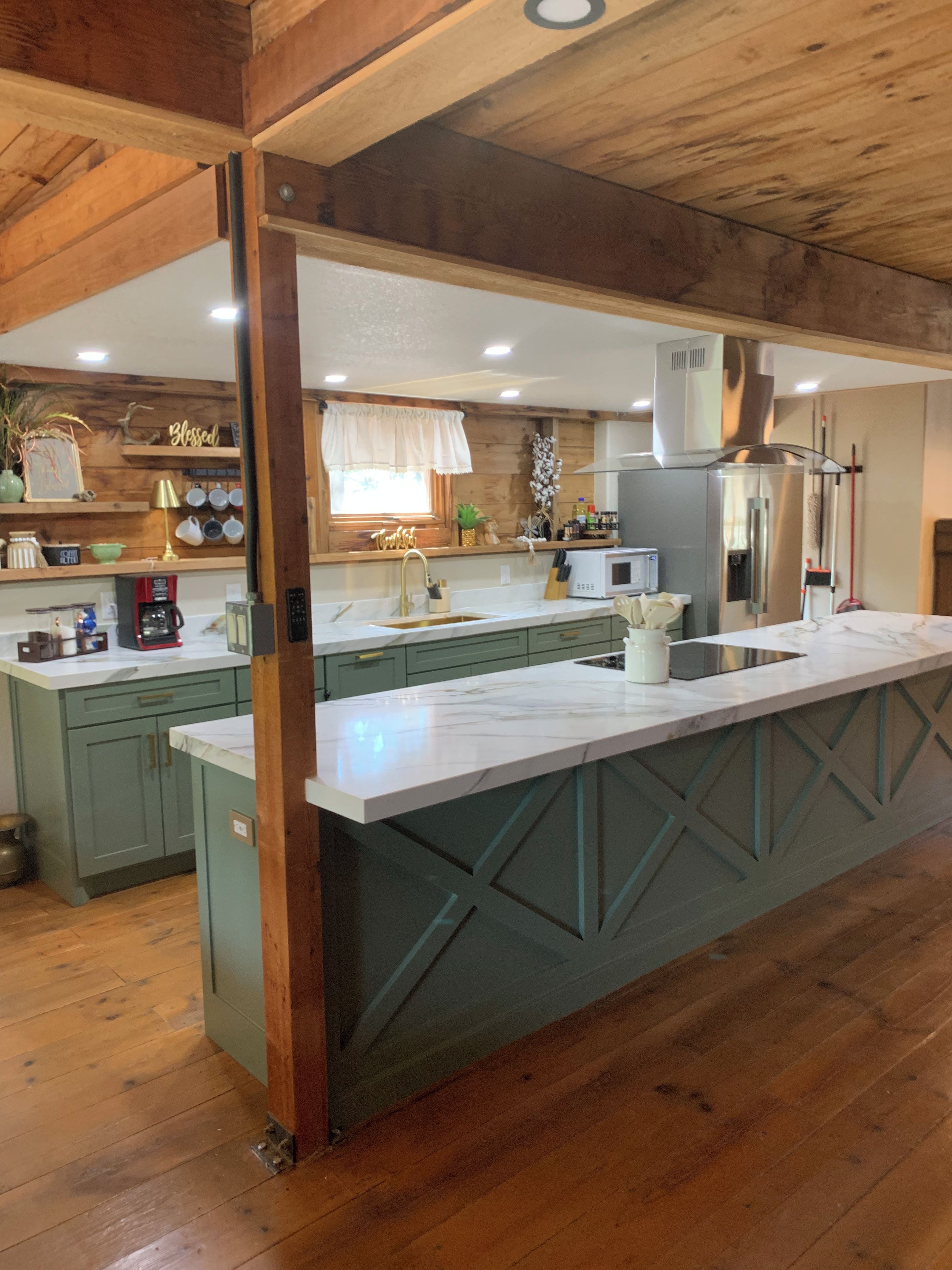 A kitchen with a large island, wooden cabinets, and a window with a curtain.
