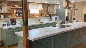 A kitchen with a large island, wooden cabinets, and a window with a curtain.