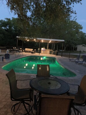 An outdoor pool area with a covered seating area, lounge chairs, and a barbecue station. - Murt’s Lodge at Red Canoe Lodge Historic Lake Whitney Resort, Totaly Reimagined (Clifton)