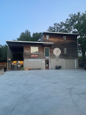 A two-story building with a 'VACANCY' sign, a garage, and a covered outdoor area. - Murt’s Lodge at Red Canoe Lodge Historic Lake Whitney Resort, Totaly Reimagined (Clifton)