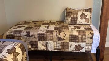 A single bed with a quilted headboard and footboard, a matching pillow, and a wooden floor.