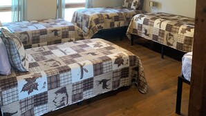 Ein Zimmer mit zwei Betten, Holzboden und schräg versiegelter Decke.