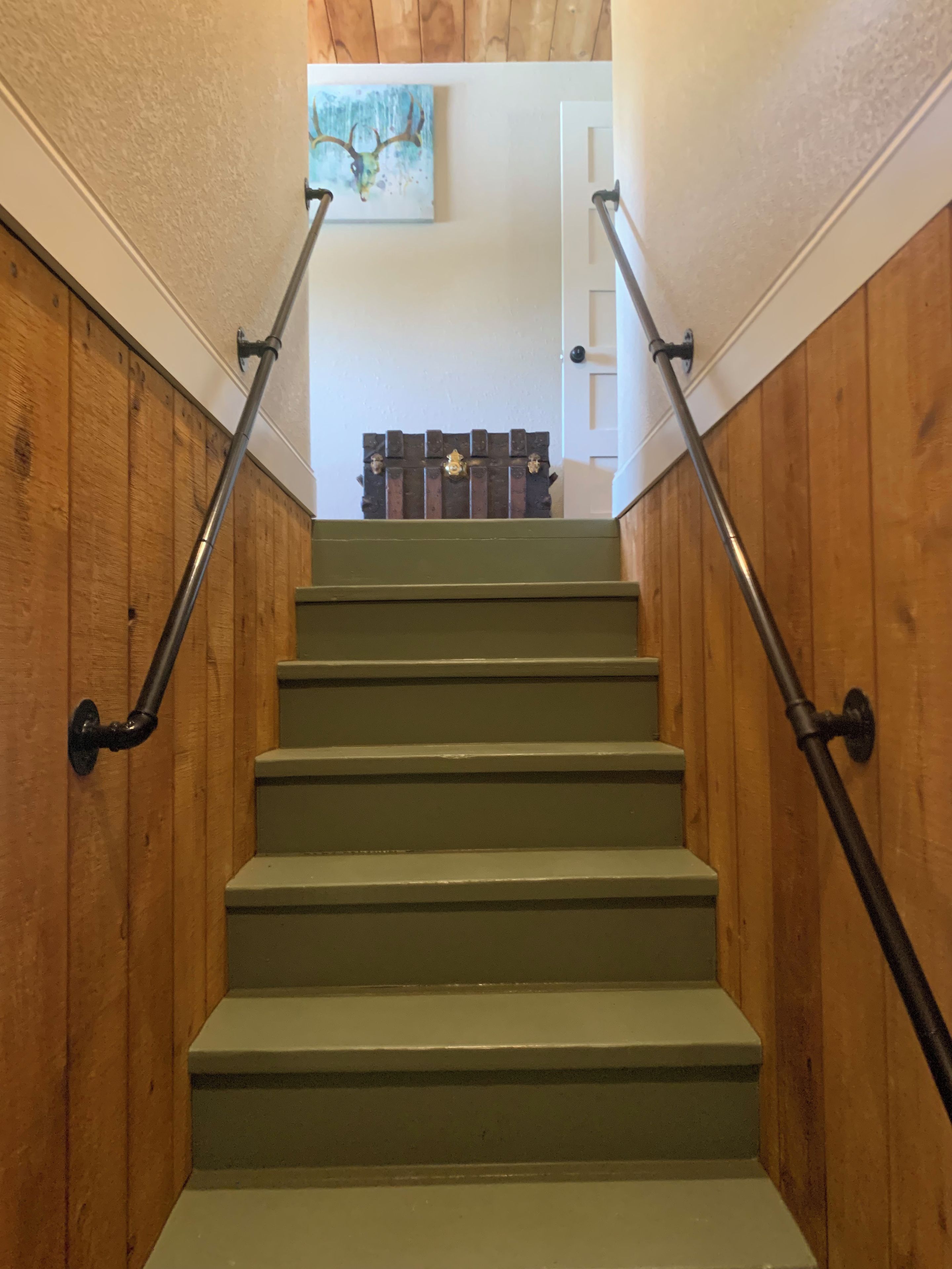 A staircase with wooden walls and metal handrails leading to a door.