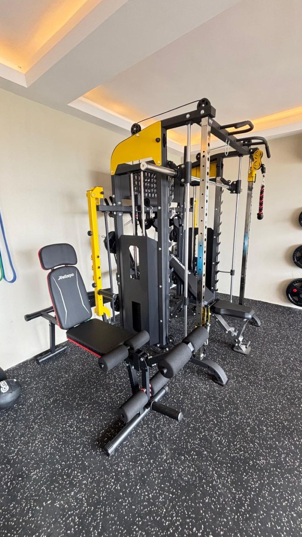 Un gimnasio con una máquina de pesas, una banca y una jaula para sentadillas.