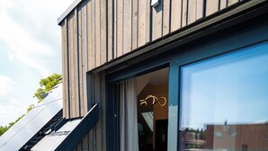 En modern byggnad med en träfasad, en entré med glasdörr och en synlig interiör med ett matområde.