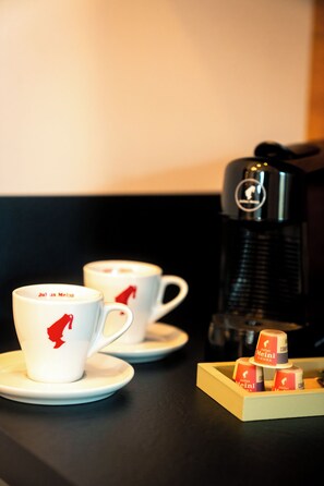 Two white cups with red logos, a coffee maker, and a tray with coffee capsules. - Vrbo Property (Erbach)