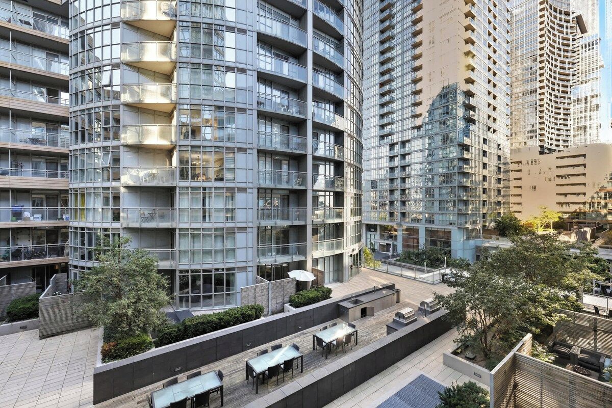A modern high-rise building with multiple balconies, outdoor seating areas, and a rooftop terrace.