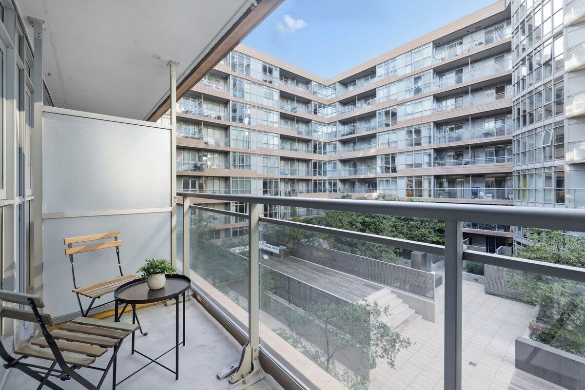 Een balkon met een tafel en stoelen, met uitzicht op een modern appartementencomplex.