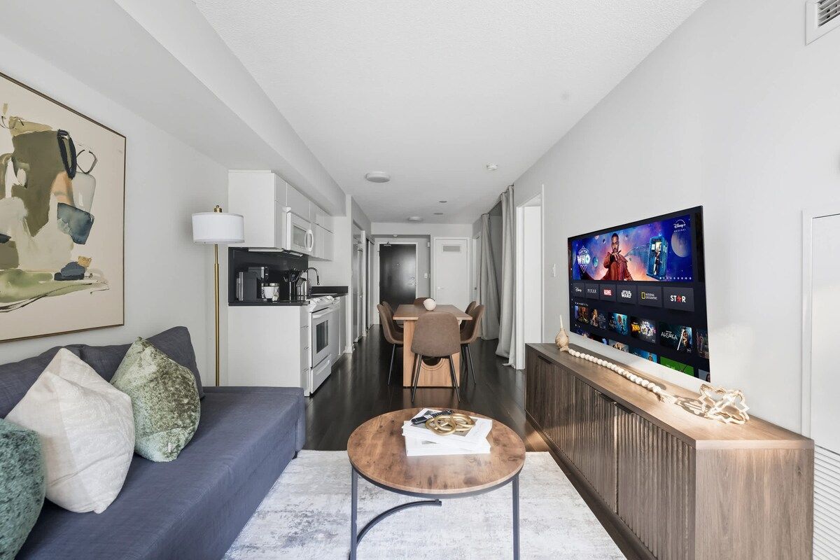 A modern living room with a sofa, coffee table, and a flat-screen TV mounted on the wall.