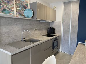 Eine moderne Küche mit integriertem Backofen, einer Kaffeemaschine und einer Uhr an der Wand.