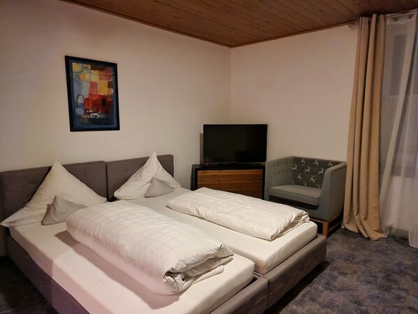 Ein Hotelzimmer mit einem Bett, einem Fernseher, einem Sessel und einem Bild an der Wand.