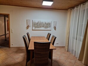 Ein Essbereich mit Holztisch und -stühlen, einem Bild an der Wand und einer Tür zu einem anderen Raum.