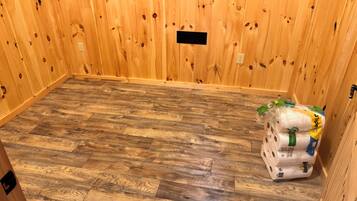 Une pièce aux murs en bois et au plancher orné d’un motif en chevrons. Un tas d’essuie-tout est posé sur le sol.