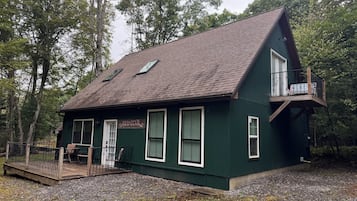 Une maison à deux étages avec un balcon, une véranda et une allée gravillonnée.