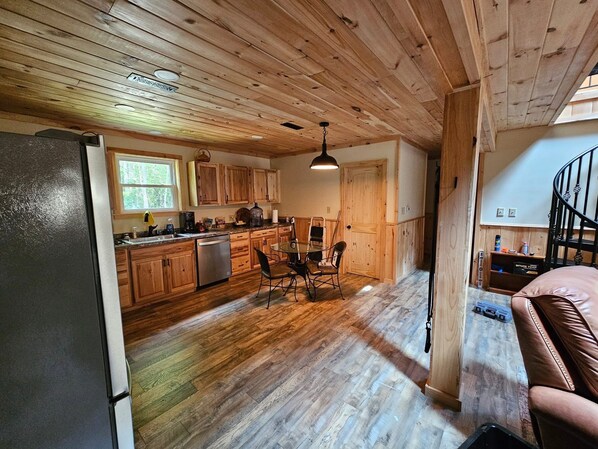 A kitchen with wooden cabinets, a refrigerator, and a dining area with a table and chairs.
