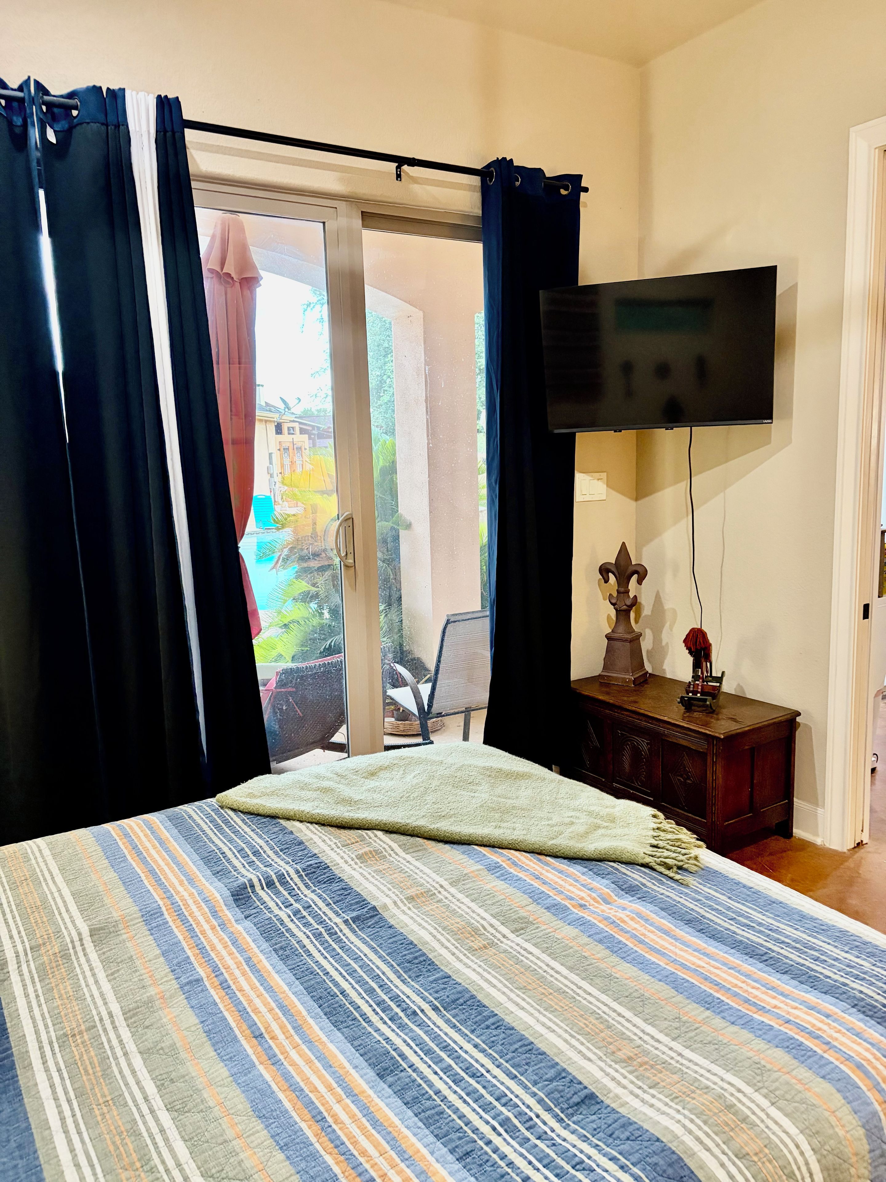 Ein Schlafzimmer mit Bett, Vorhängen, einem Fernseher und Blick ins Freie.