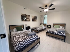 A bedroom with two beds, a ceiling fan, and artwork on the wall. - The 5th Street Retreat - Private Fenced Yard (Smithfield)