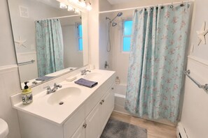 Ein Badezimmer mit zwei Waschbecken, einer Dusche und einem großen Spiegel.